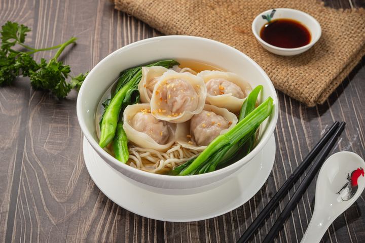 Handmade dumplings over soup noodles with leafy greens