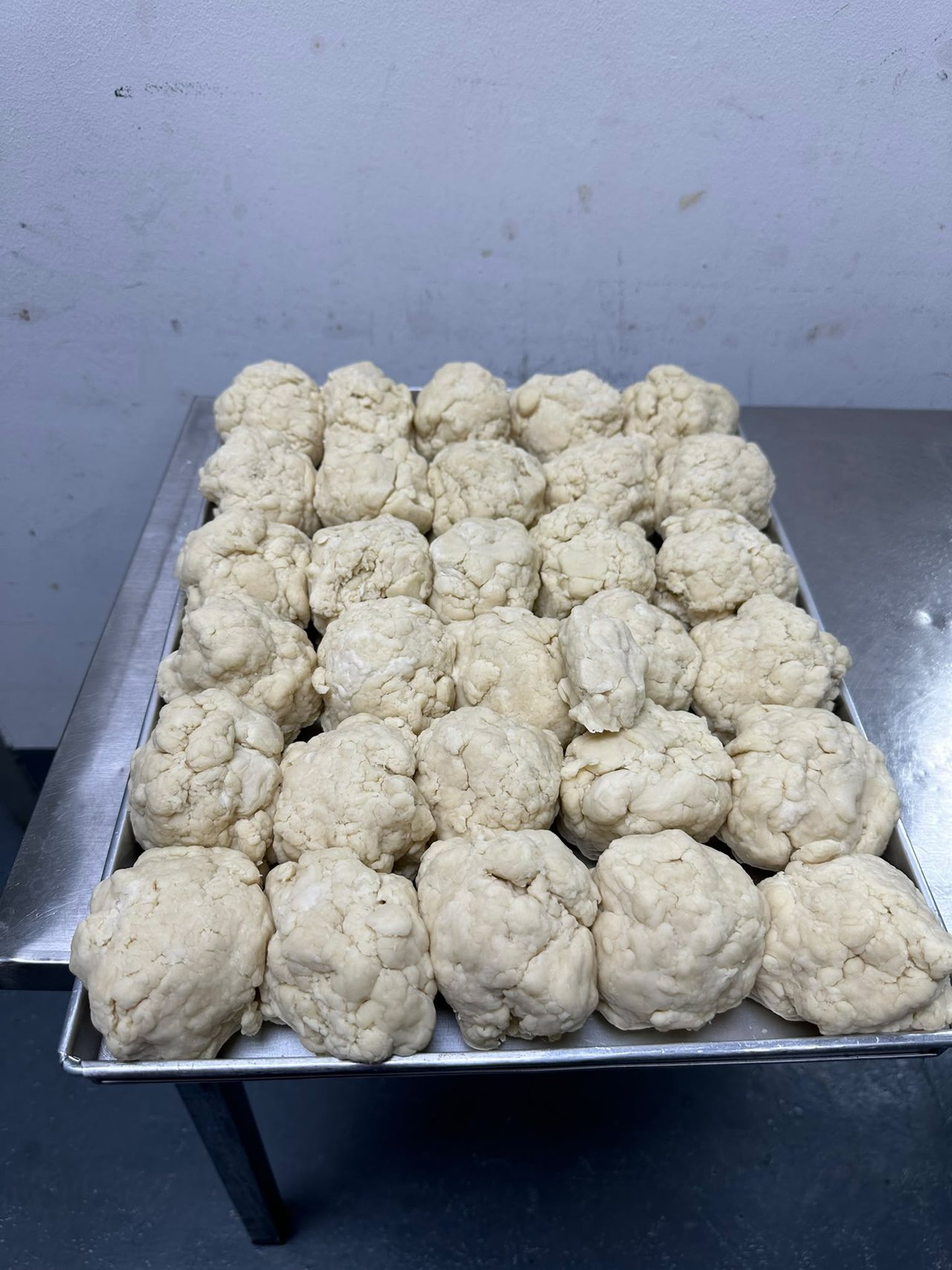 Dough portions arranged on a metal tray in the kitchen